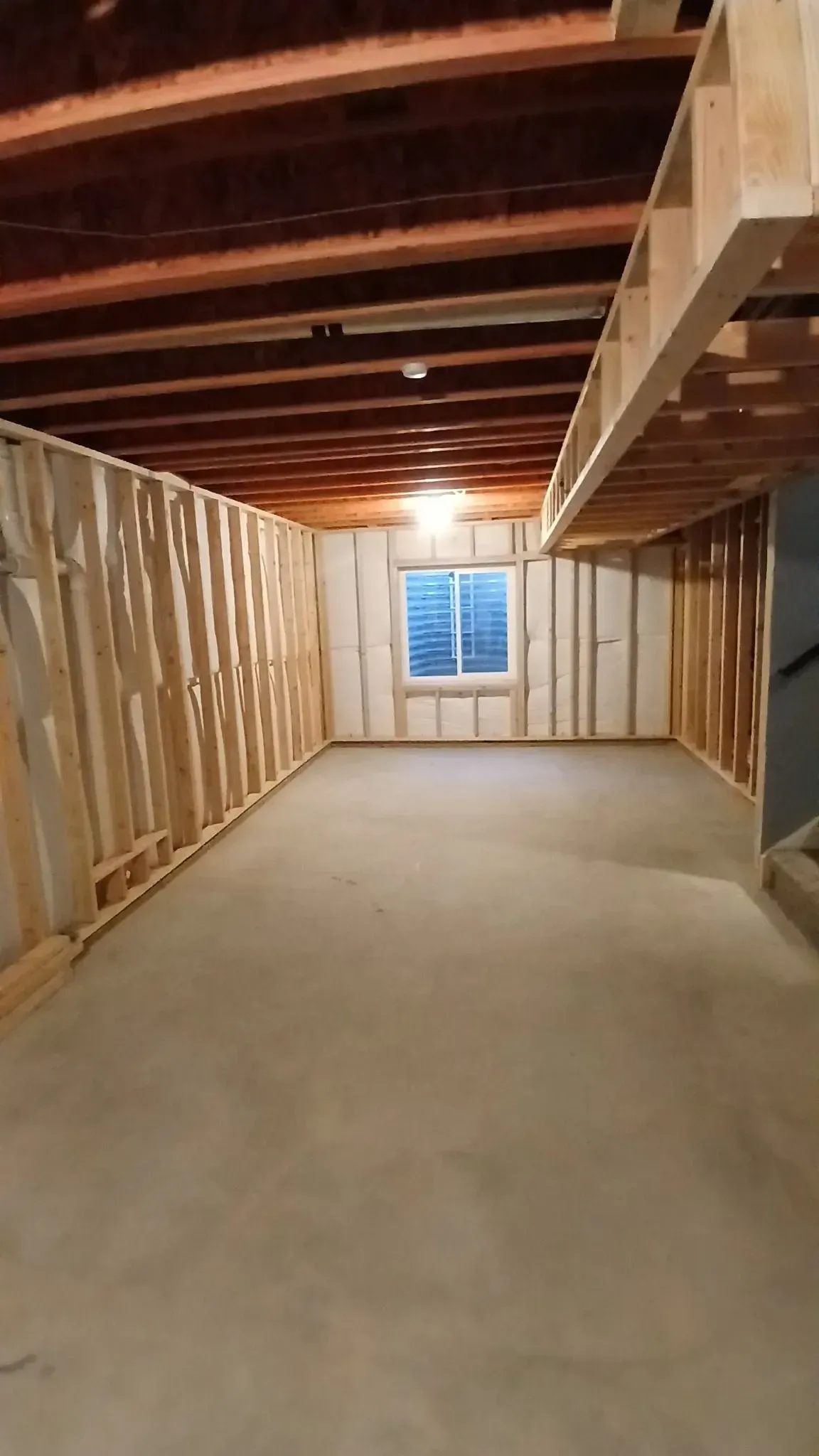 Beige brick house with dark brown metal roof and gutters, against a cloudy sky.