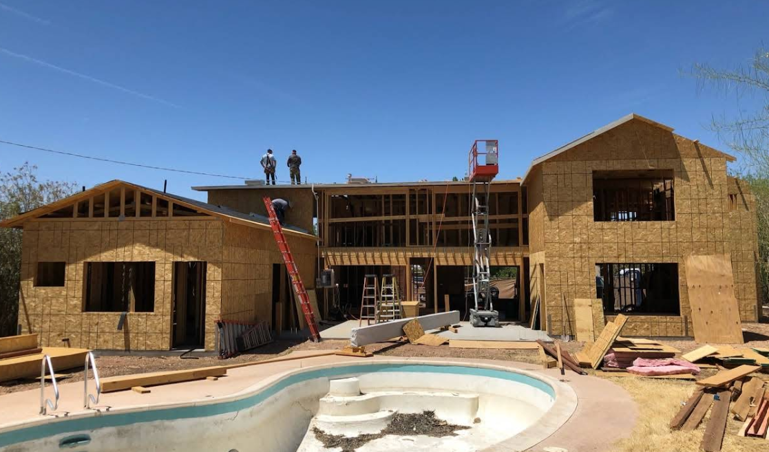 Carpenter wearing a tool belt, working on wooden framing of a building.