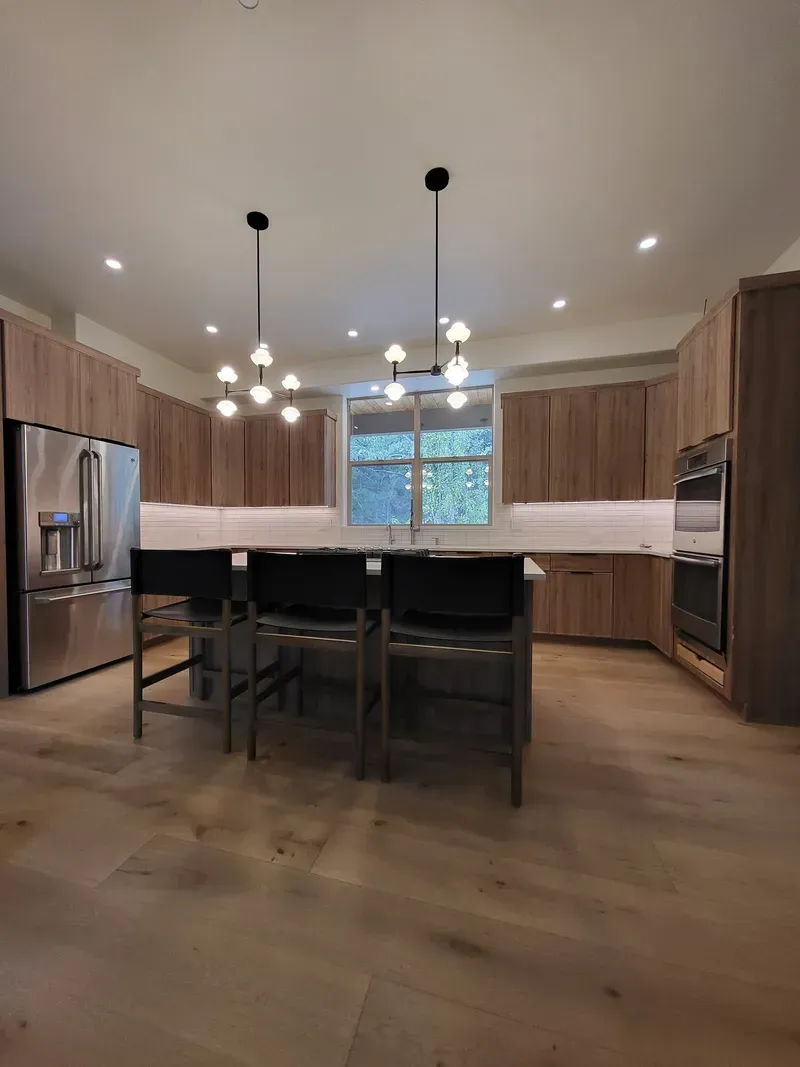 Modern kitchen with wood cabinets, stainless steel appliances, and island with pendant lights.