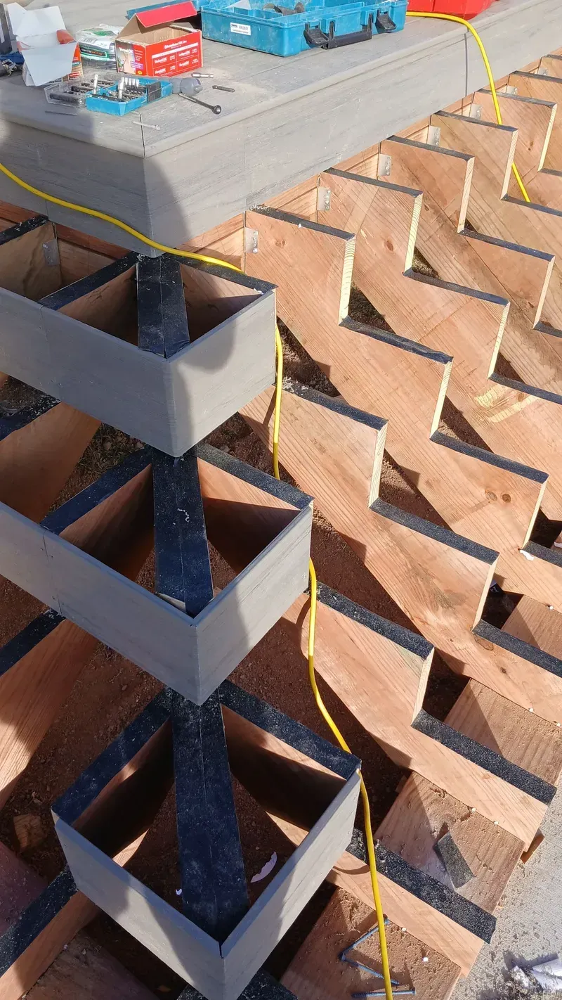 Construction site with wooden framework and tiered boxes; yellow electrical wiring.