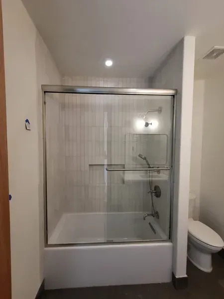 Bathroom with a shower/tub, glass sliding doors, and a toilet.