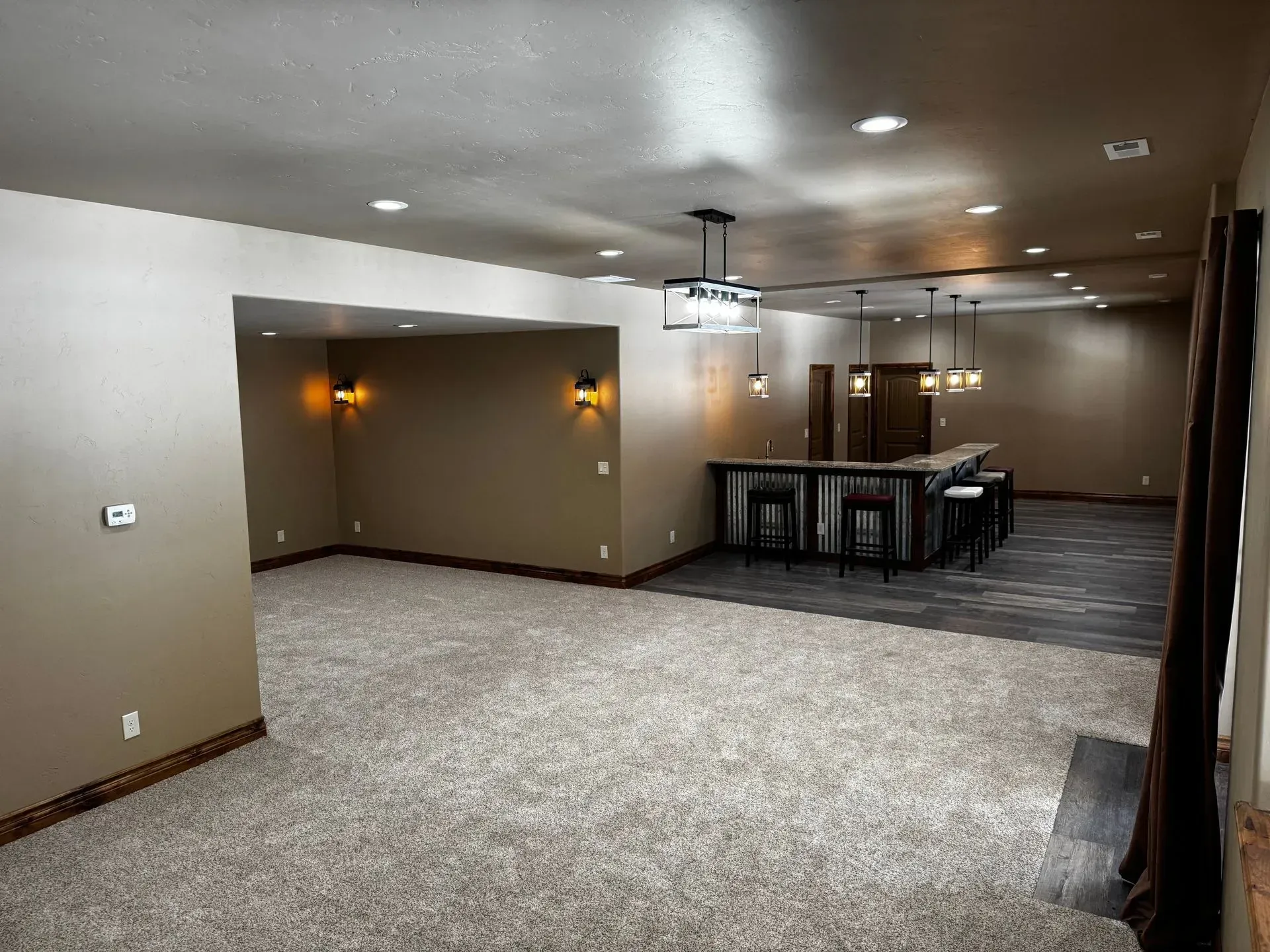 Spacious finished basement with bar, carpet, recessed lighting, and neutral-colored walls.