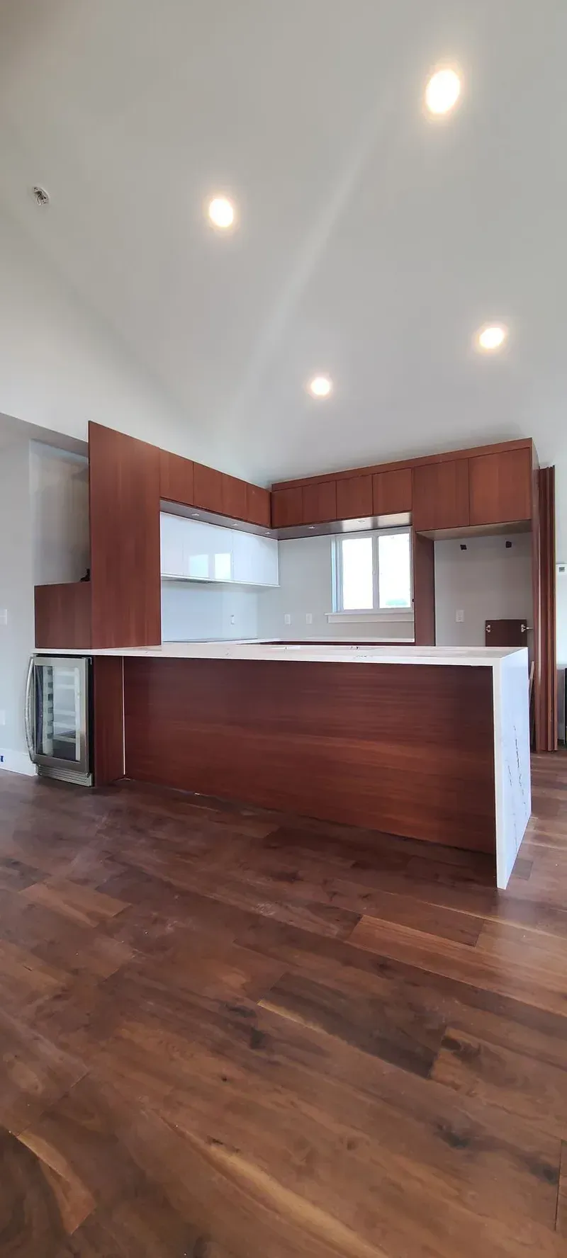 Modern kitchen with dark wood cabinets and island, white countertops, and wood flooring.
