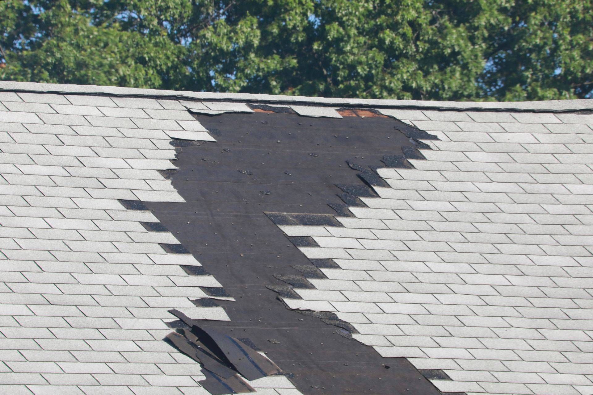Roofer in yellow hard hat, using a tool on a white metal roof under a blue sky.