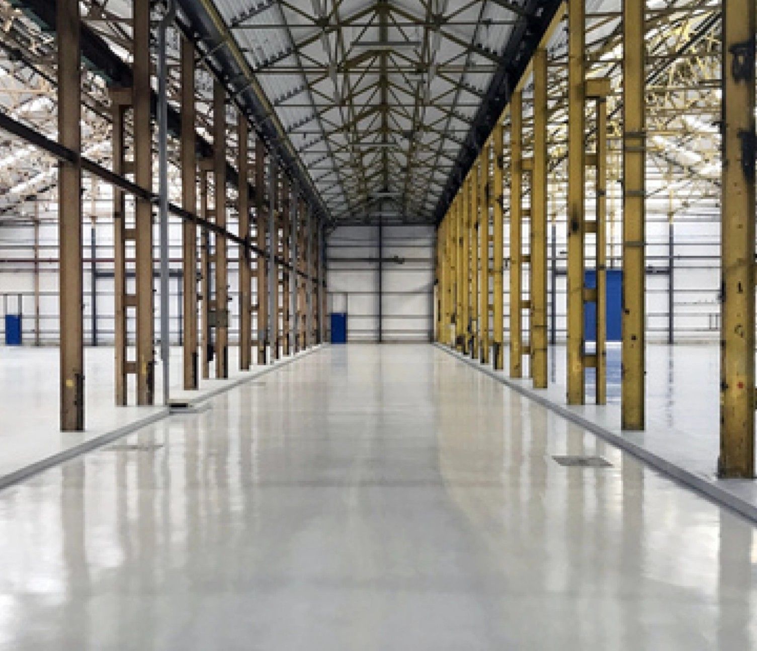 An empty warehouse with a concrete floor and wooden beams