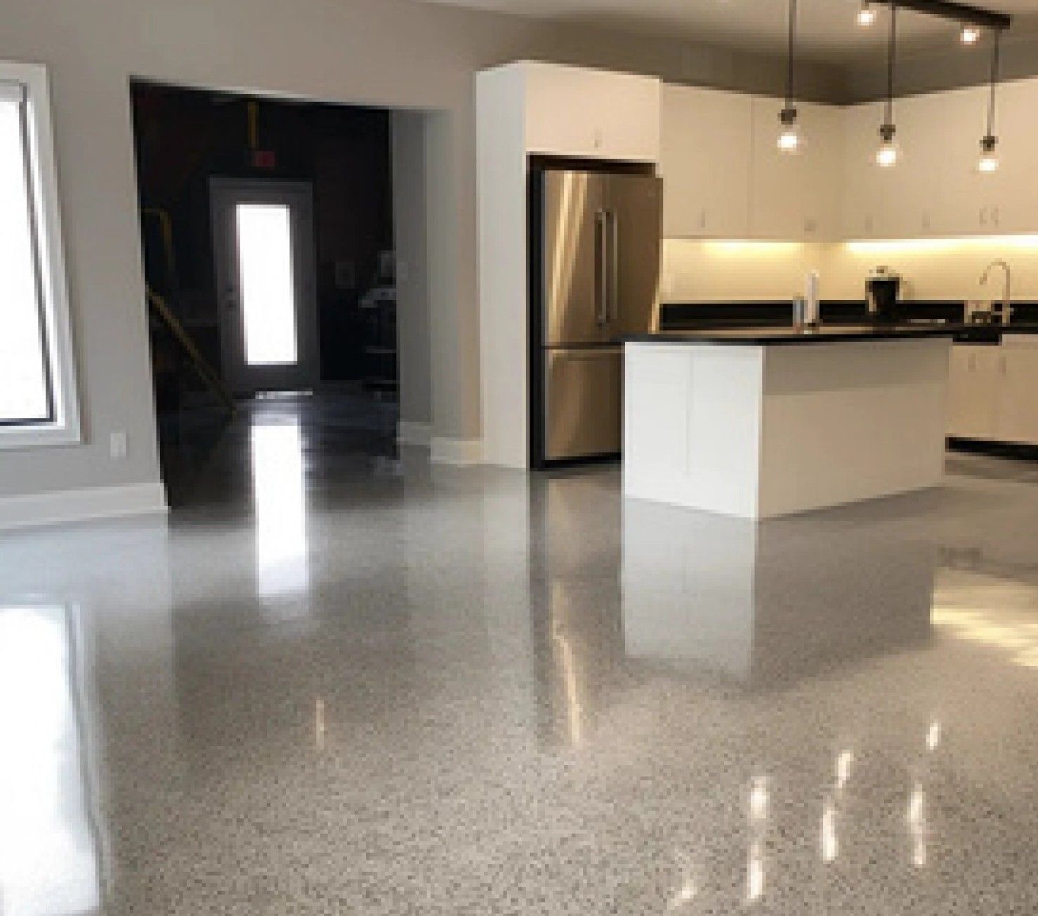 A kitchen with a large island and a stainless steel refrigerator