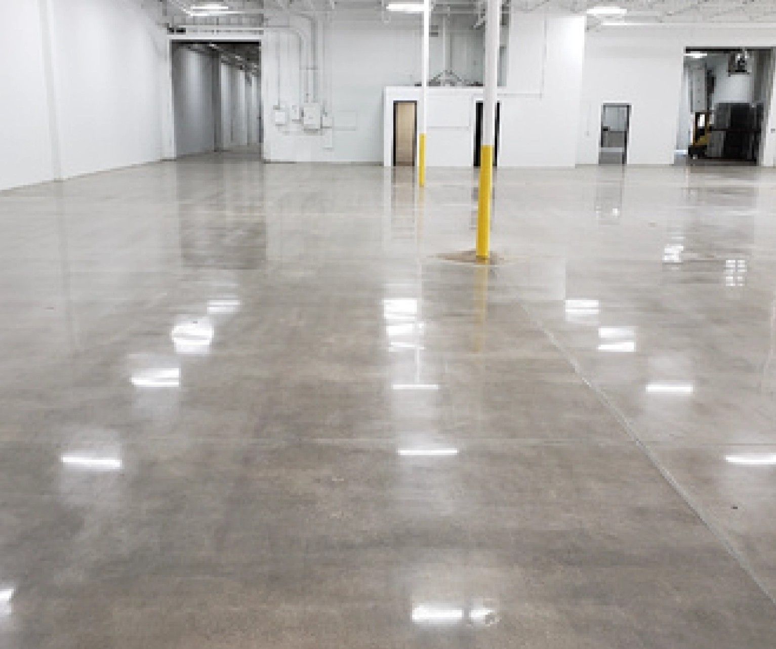 A large empty warehouse with a shiny concrete floor and white walls.