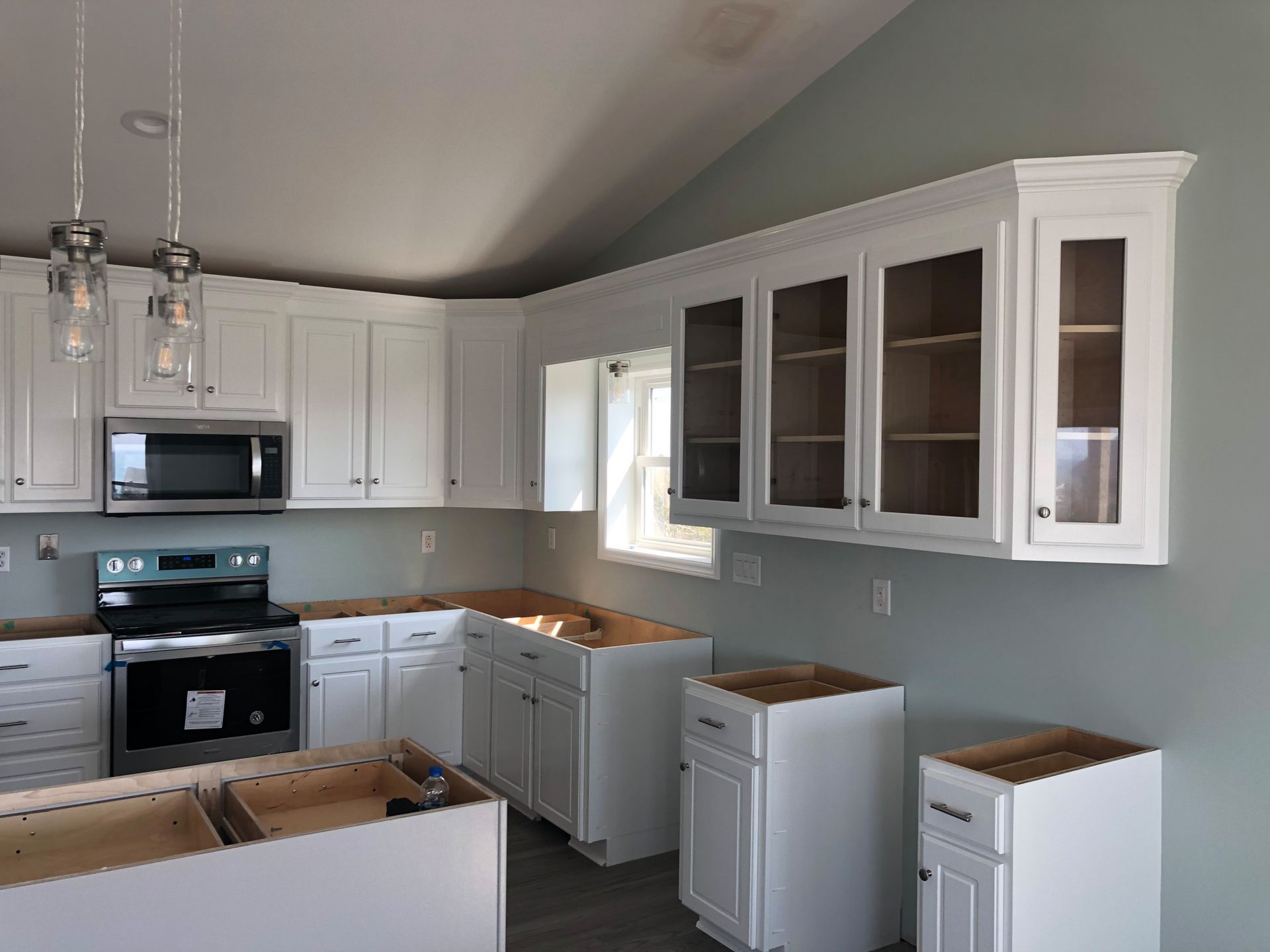 A kitchen with white cabinets , a stove , and a microwave.