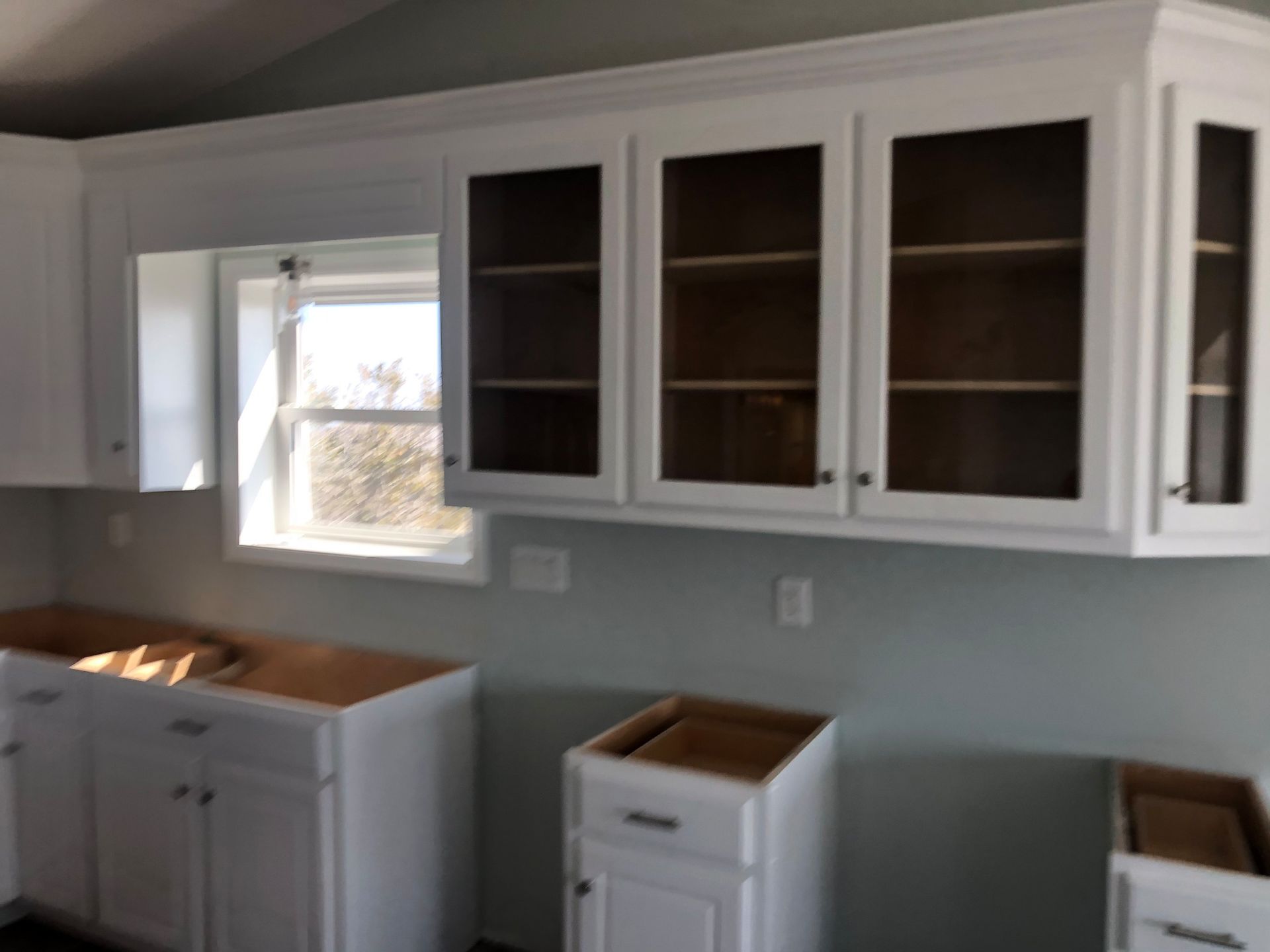 A kitchen with white cabinets and a window