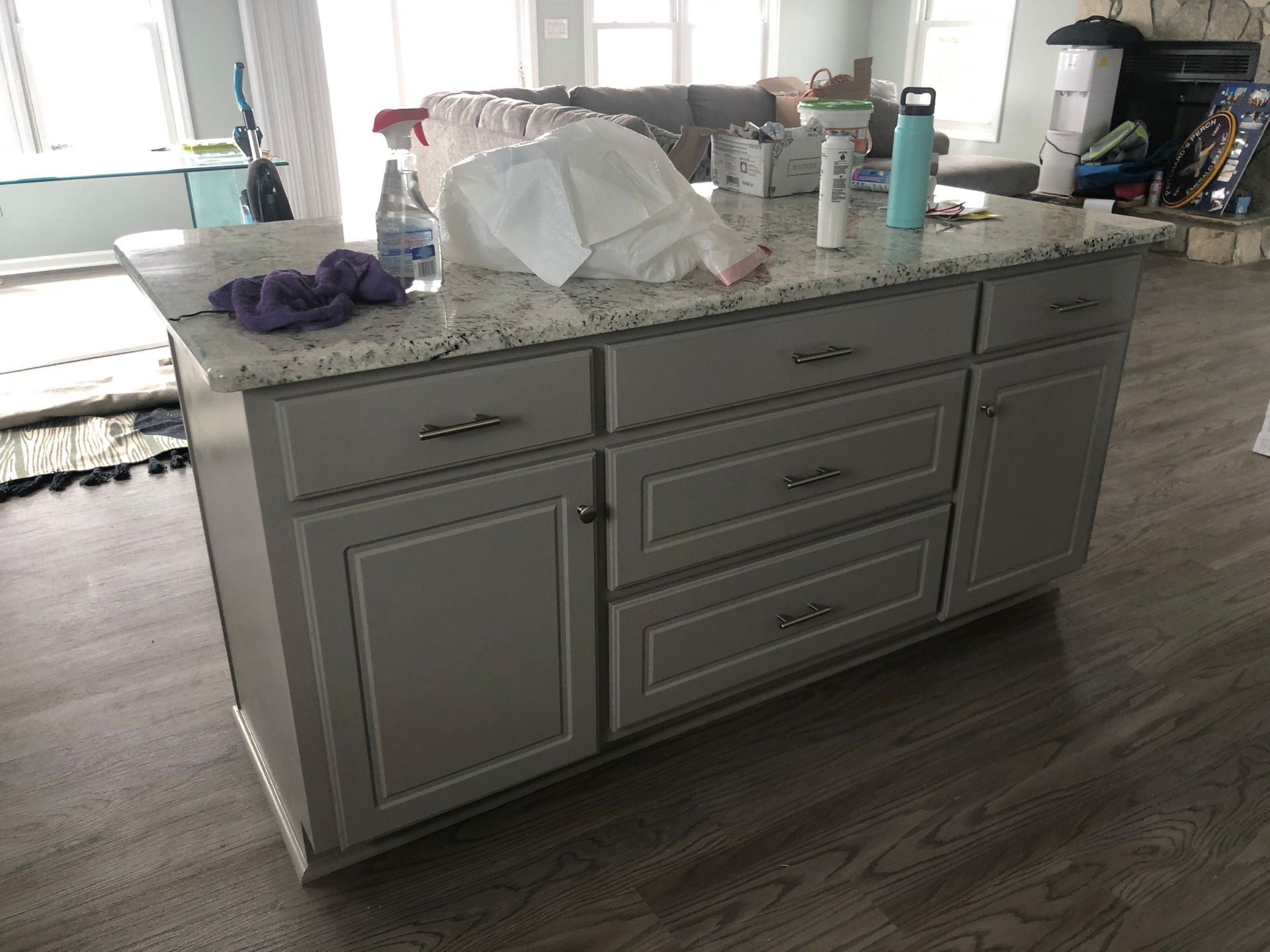 A kitchen island with drawers and a granite counter top in a living room.