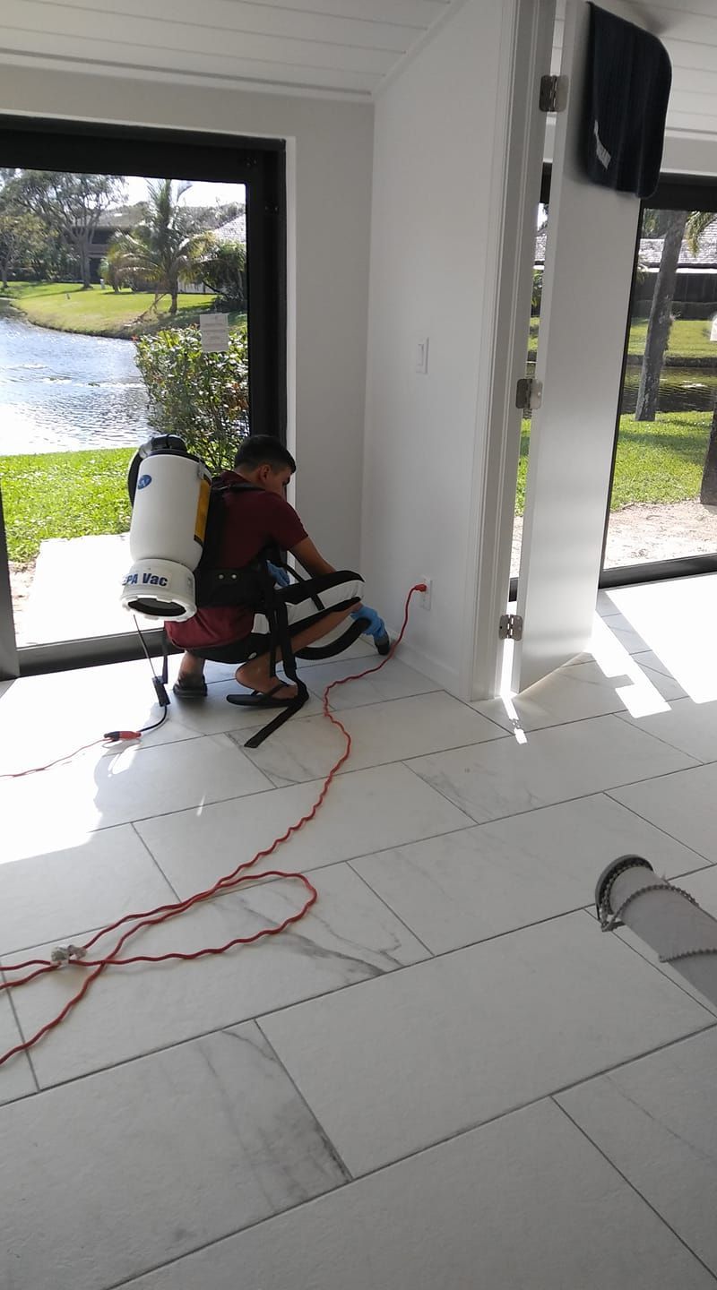 A man is sitting on a chair in a room with a vacuum cleaner.