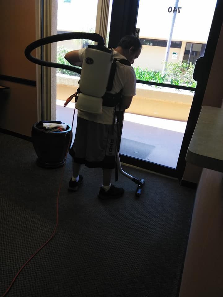 A man wearing a backpack vacuum cleaner is cleaning a window