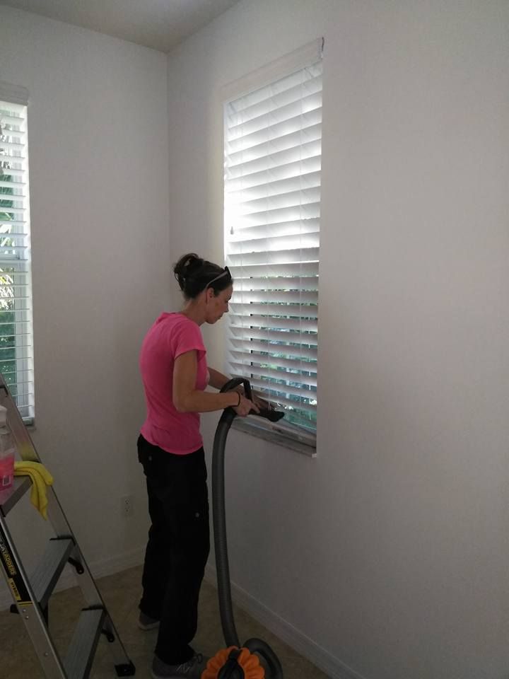 A woman is cleaning a window with a vacuum cleaner.