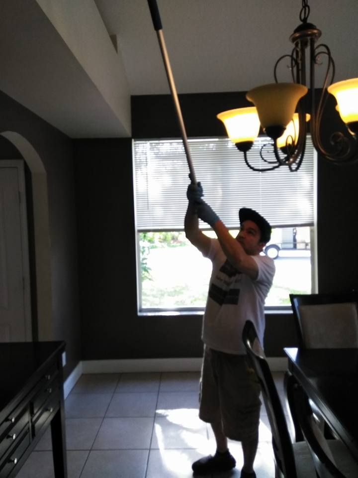 A man is holding a long pole in a dining room