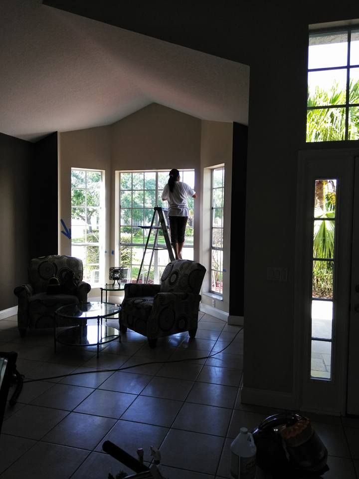 A woman is standing on a ladder in a living room
