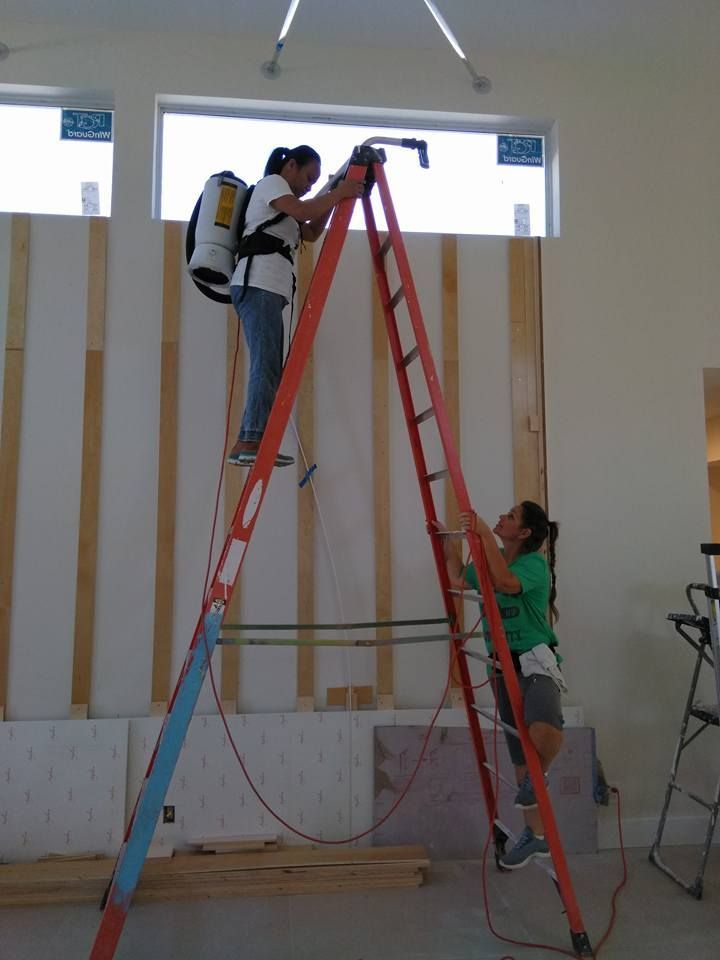 Two people are working on a ladder in a room