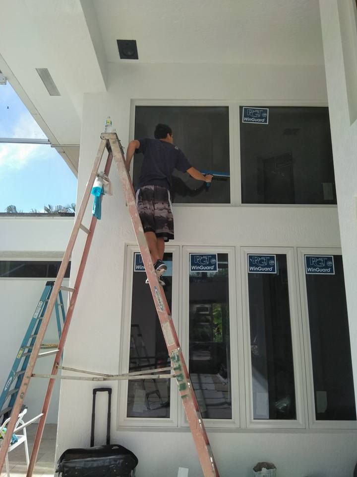 A man is standing on a ladder cleaning a window.