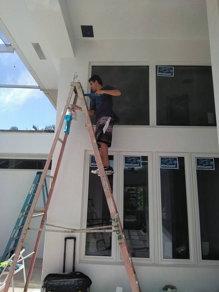 A man is standing on a ladder cleaning a window.