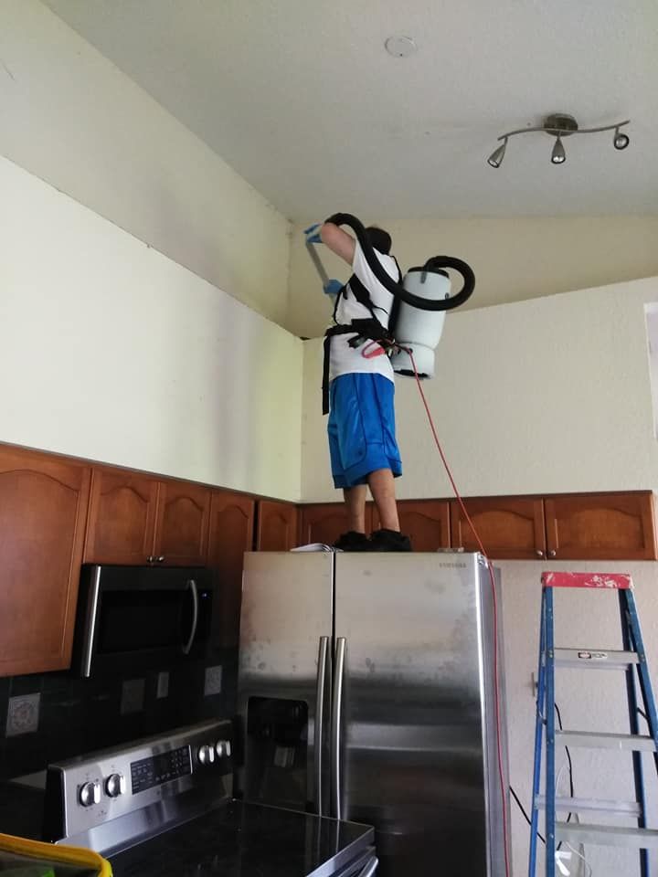 A man is spraying a ceiling in a kitchen