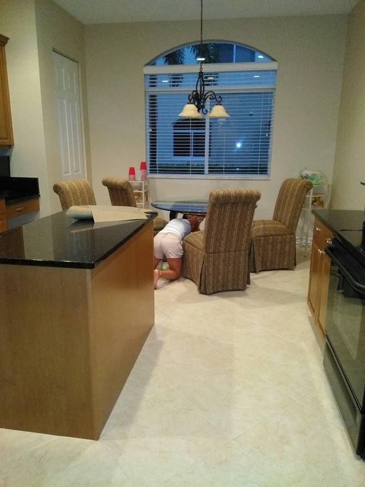 A person is crawling under a table in a kitchen