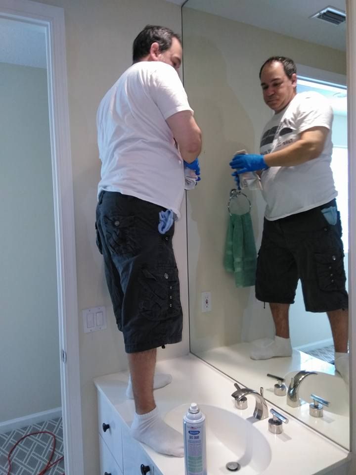 A man is standing in front of a bathroom mirror cleaning it
