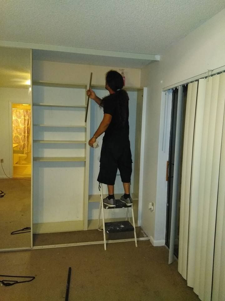 A man standing on a ladder measuring a wall