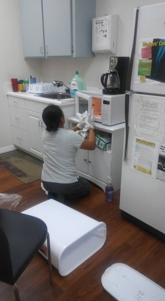 A woman is cleaning a microwave in a kitchen.
