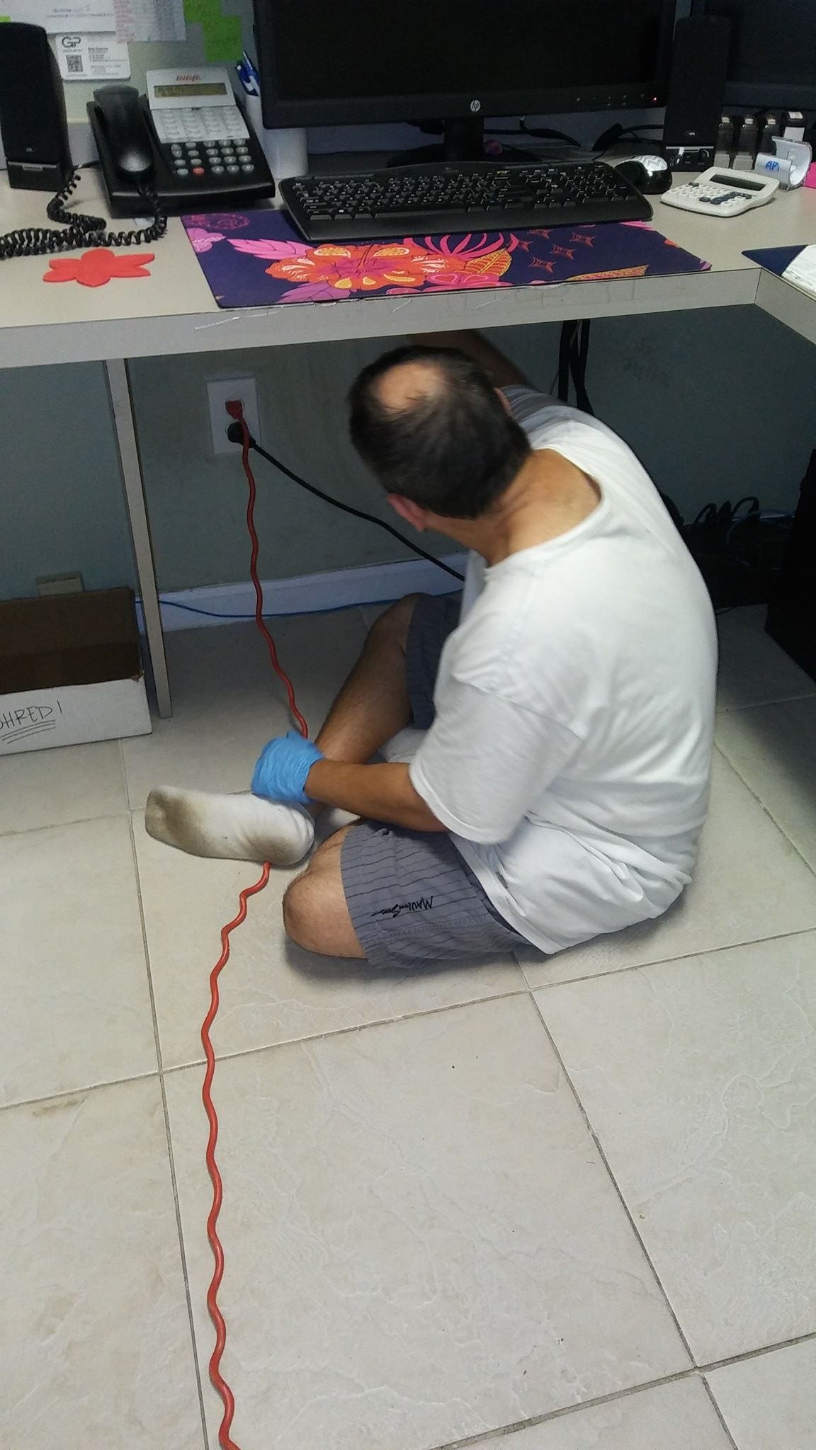 A man is sitting on the floor working on a computer