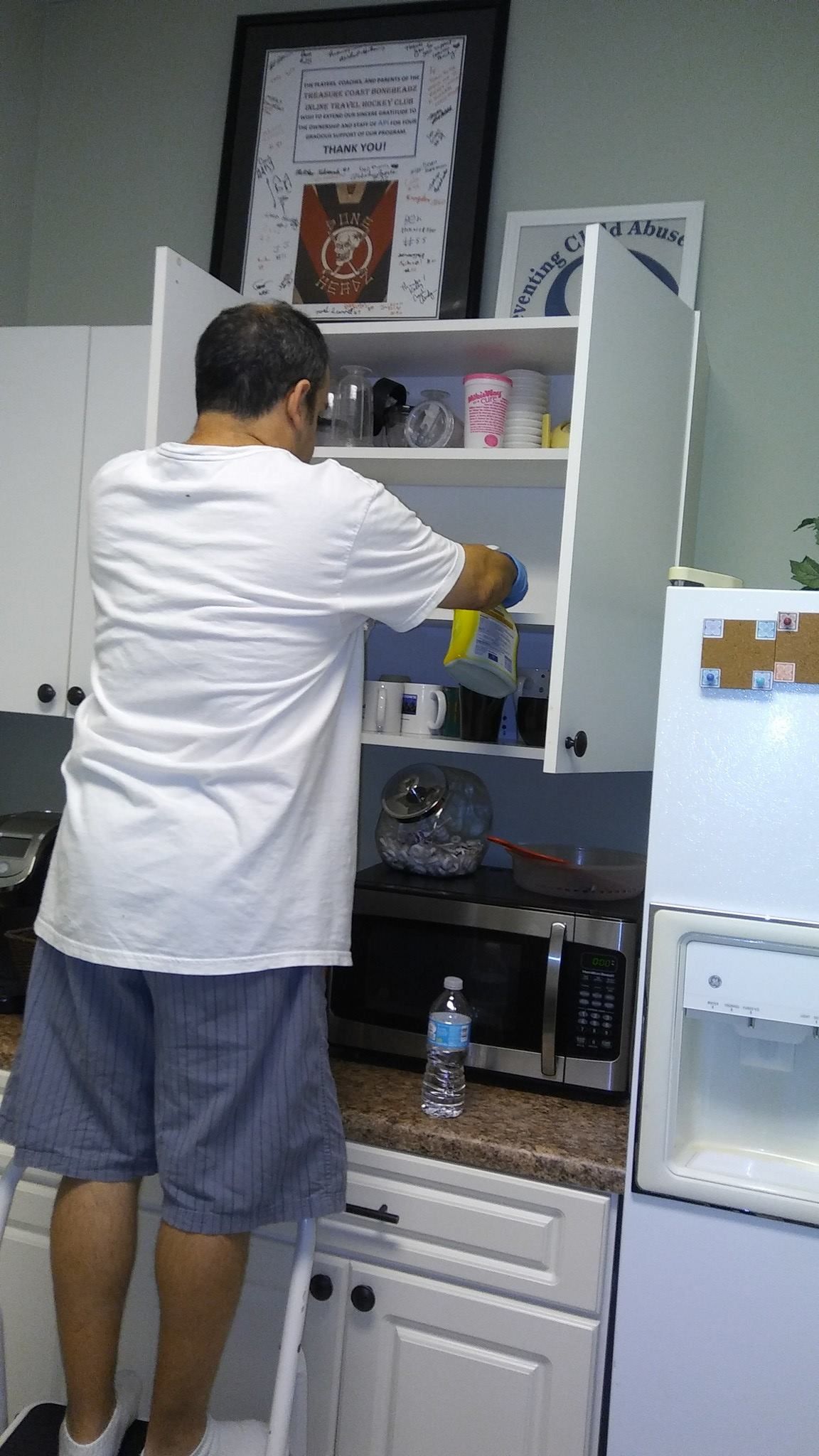 A man is standing in a kitchen looking into a cabinet.