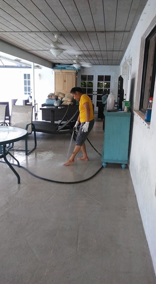 A man is cleaning the floor of a living room with a hose.