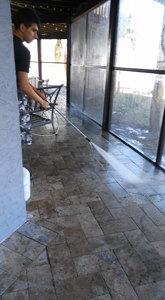 A man is cleaning a patio with a high pressure washer.