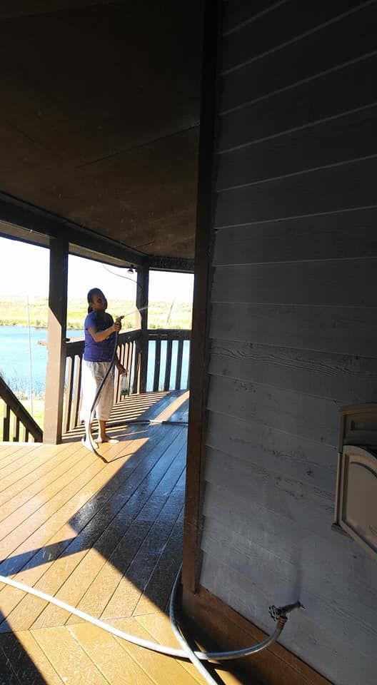 A woman is standing on a porch with a hose.