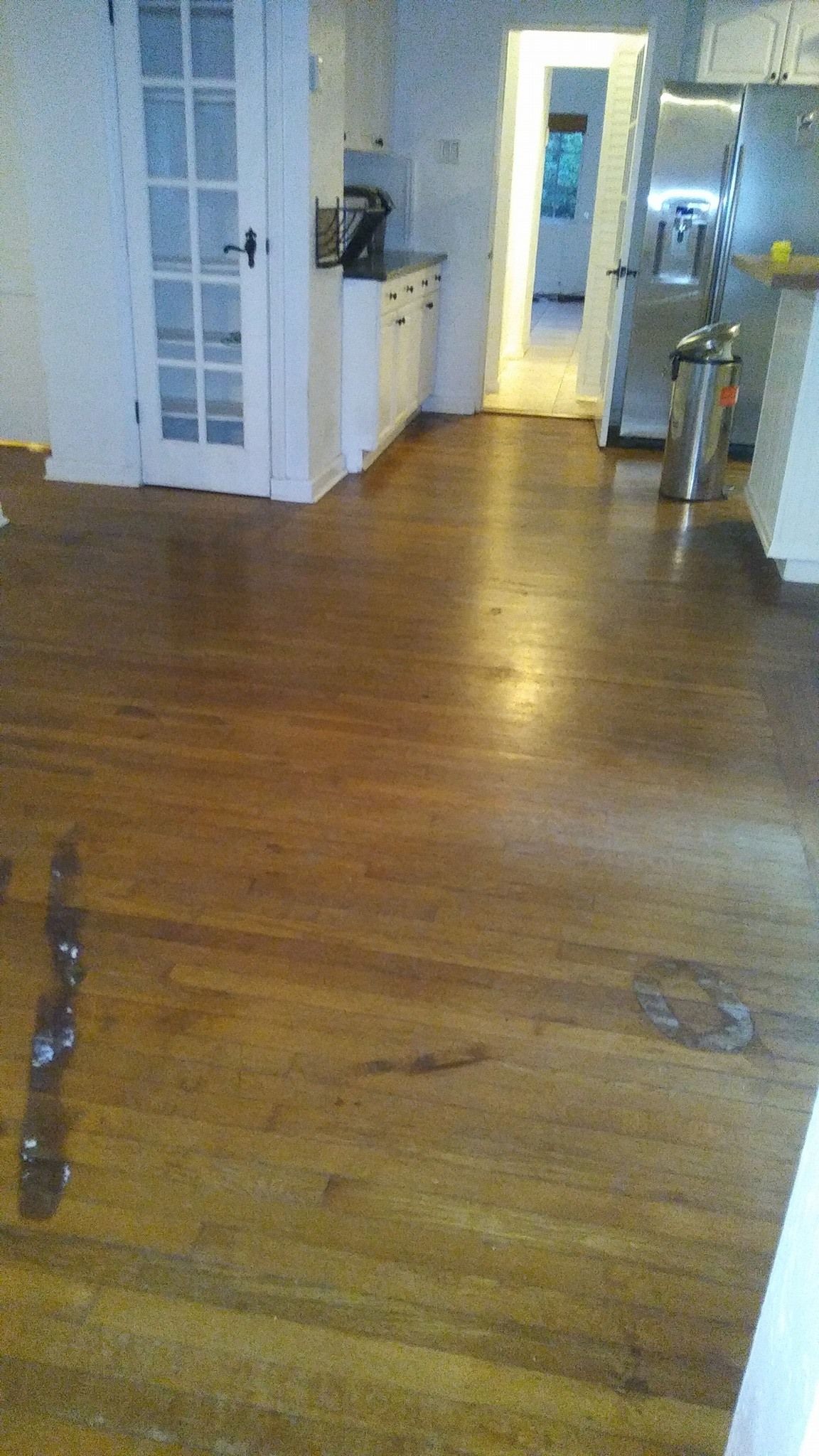 A kitchen with hardwood floors and white cabinets and a refrigerator.