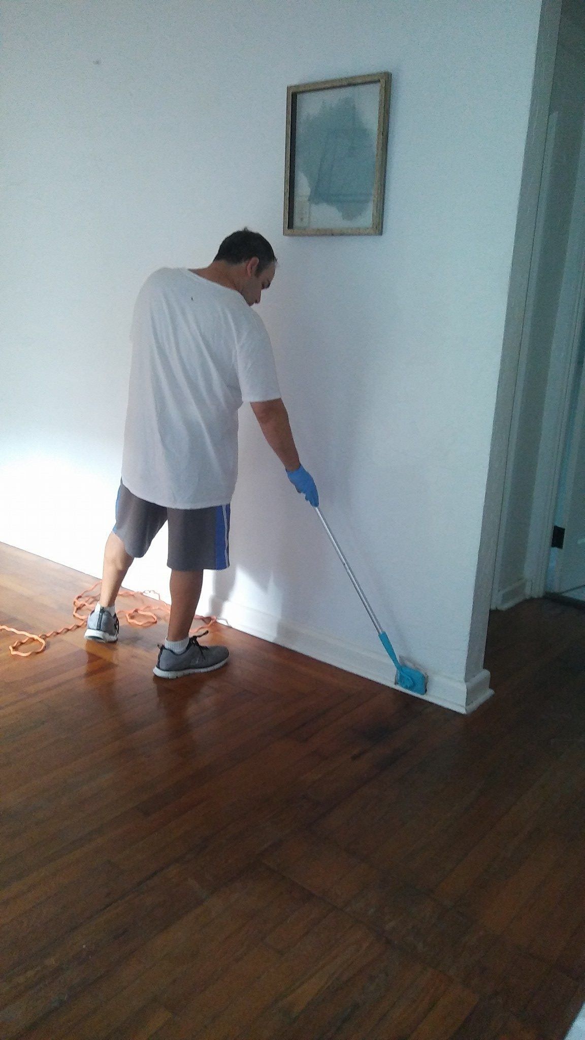 A man is cleaning the floor with a mop in a living room.