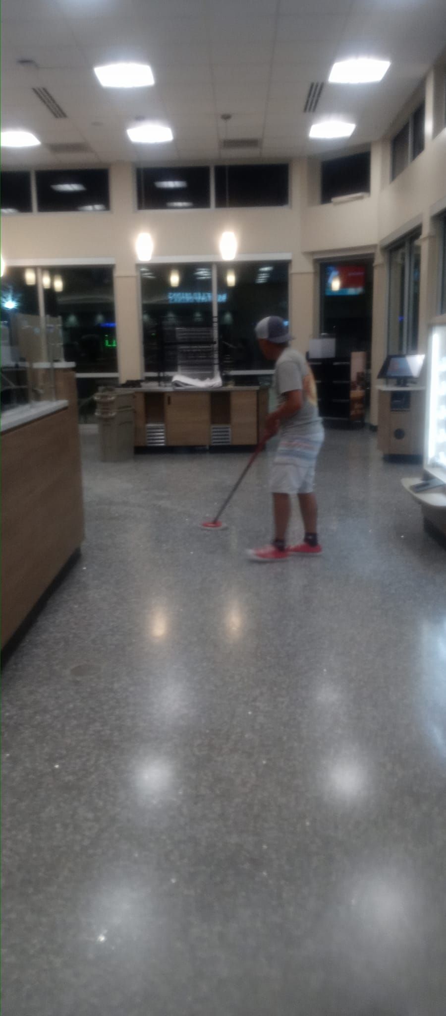 A man is cleaning the floor of a restaurant with a mop.