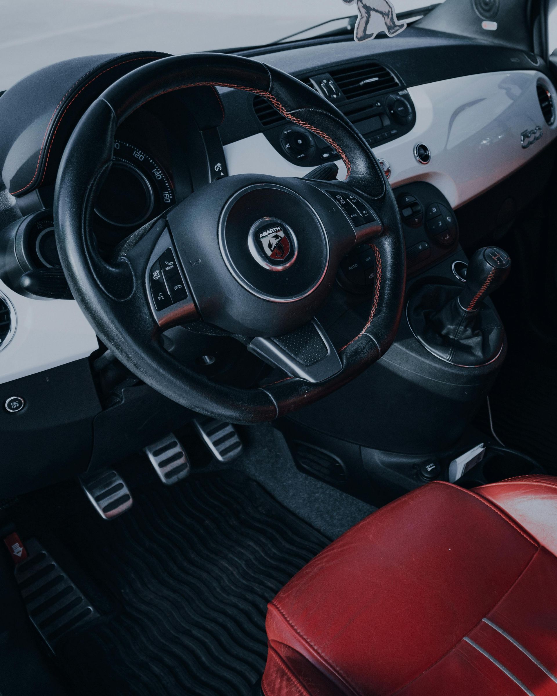 The inside of a car with a steering wheel and red seats