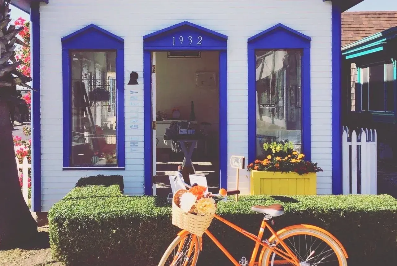 An orange bicycle is parked in front of a blue and white house.