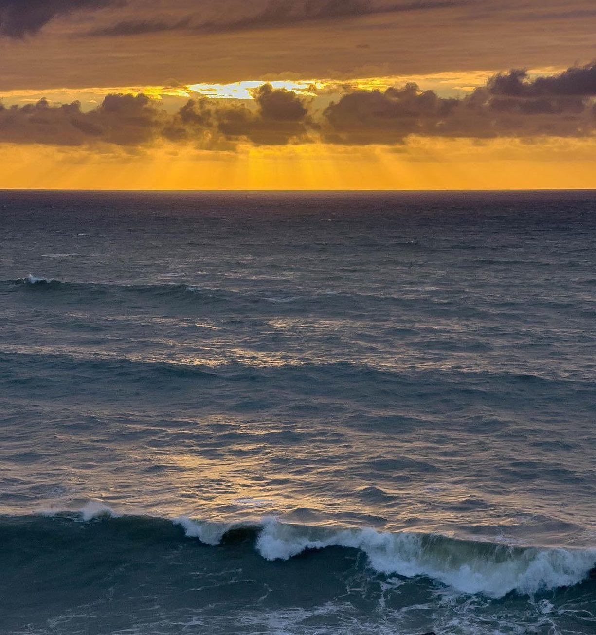 The sun is shining through the clouds over the ocean