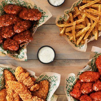 There are many different types of chicken wings and french fries on the table.