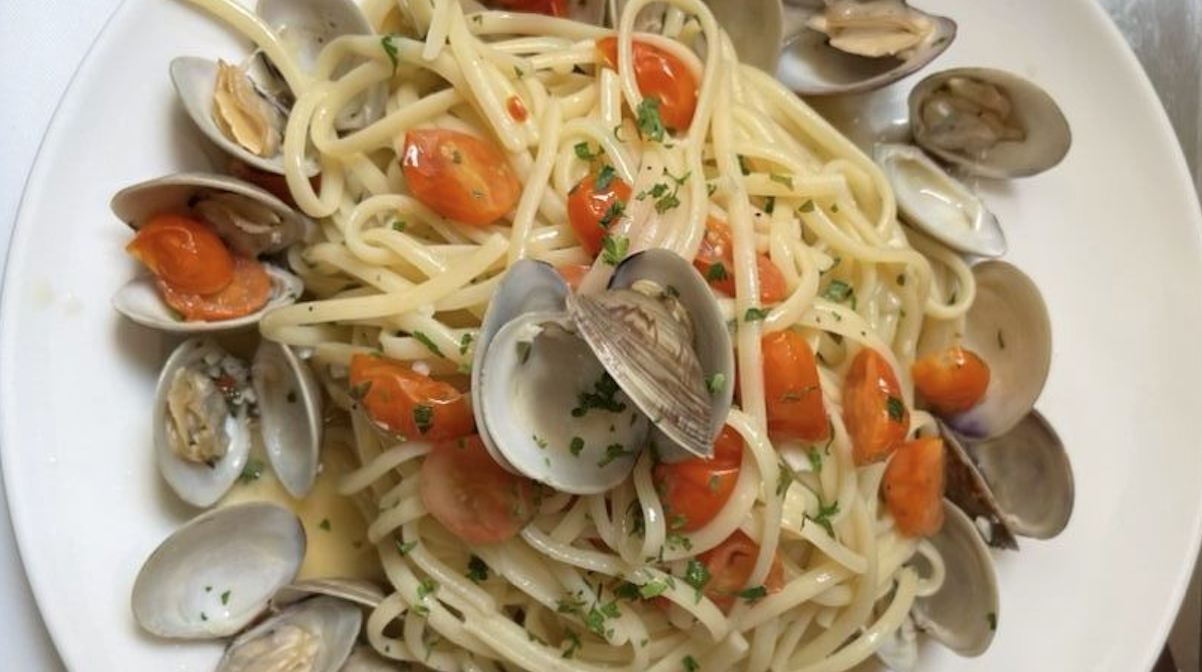 A white plate topped with spaghetti , clams and tomatoes.