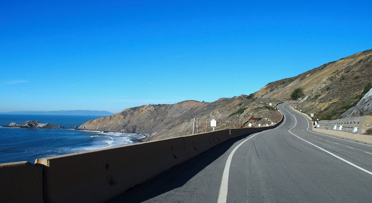 A road going through a cliff next to the ocean.