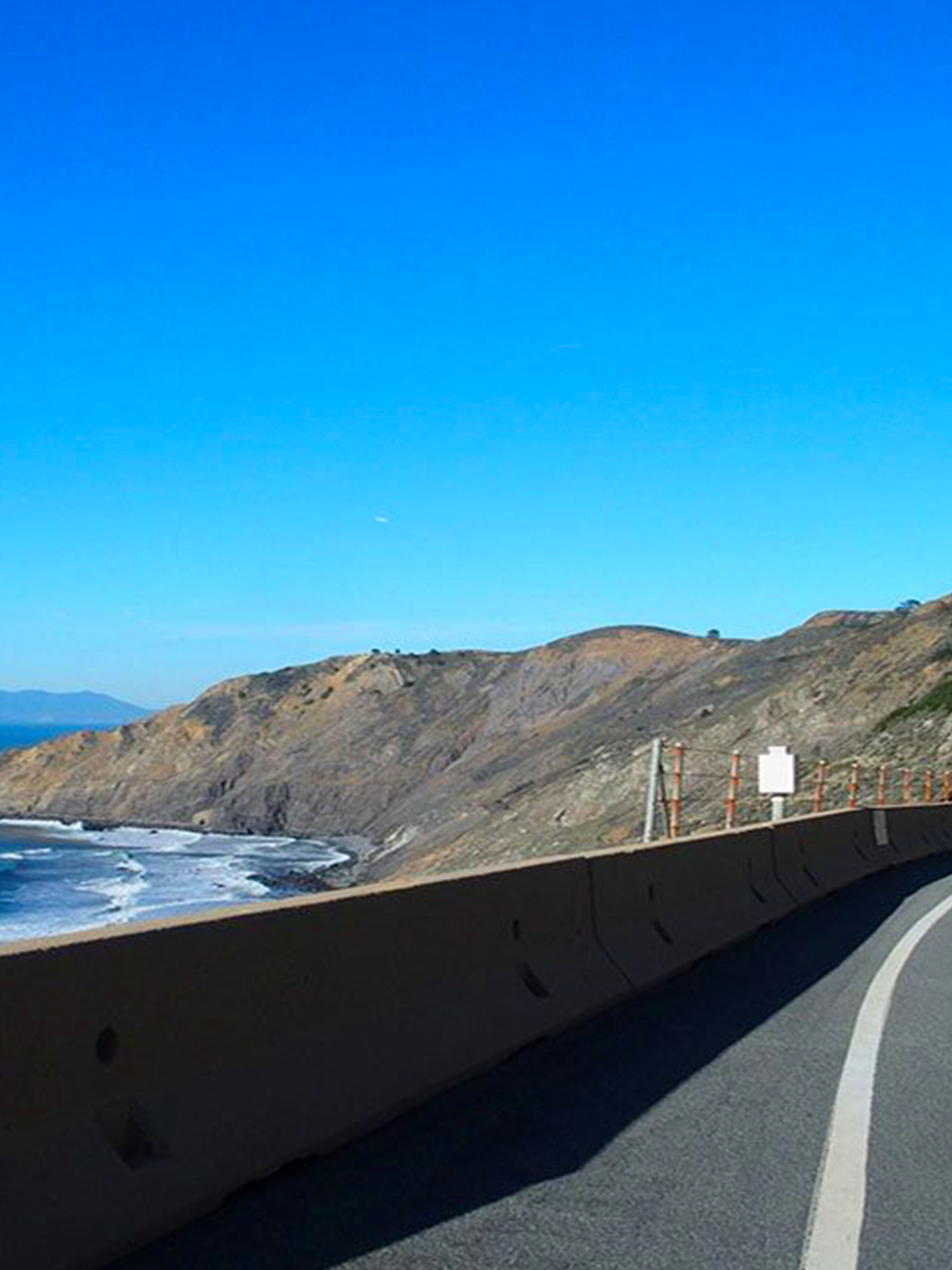 A road with a cliff and ocean in the background