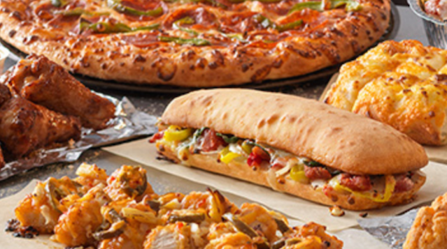 A variety of pizzas and sandwiches are sitting on a table.