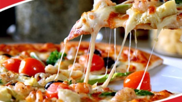A slice of pizza is being taken out of a pizza on a plate.