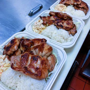 Three styrofoam containers filled with rice and meat are sitting on a counter.