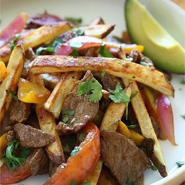 A close up of a plate of food with meat and french fries