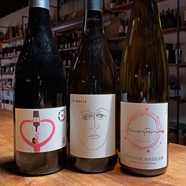 Three bottles of wine are sitting on a wooden table