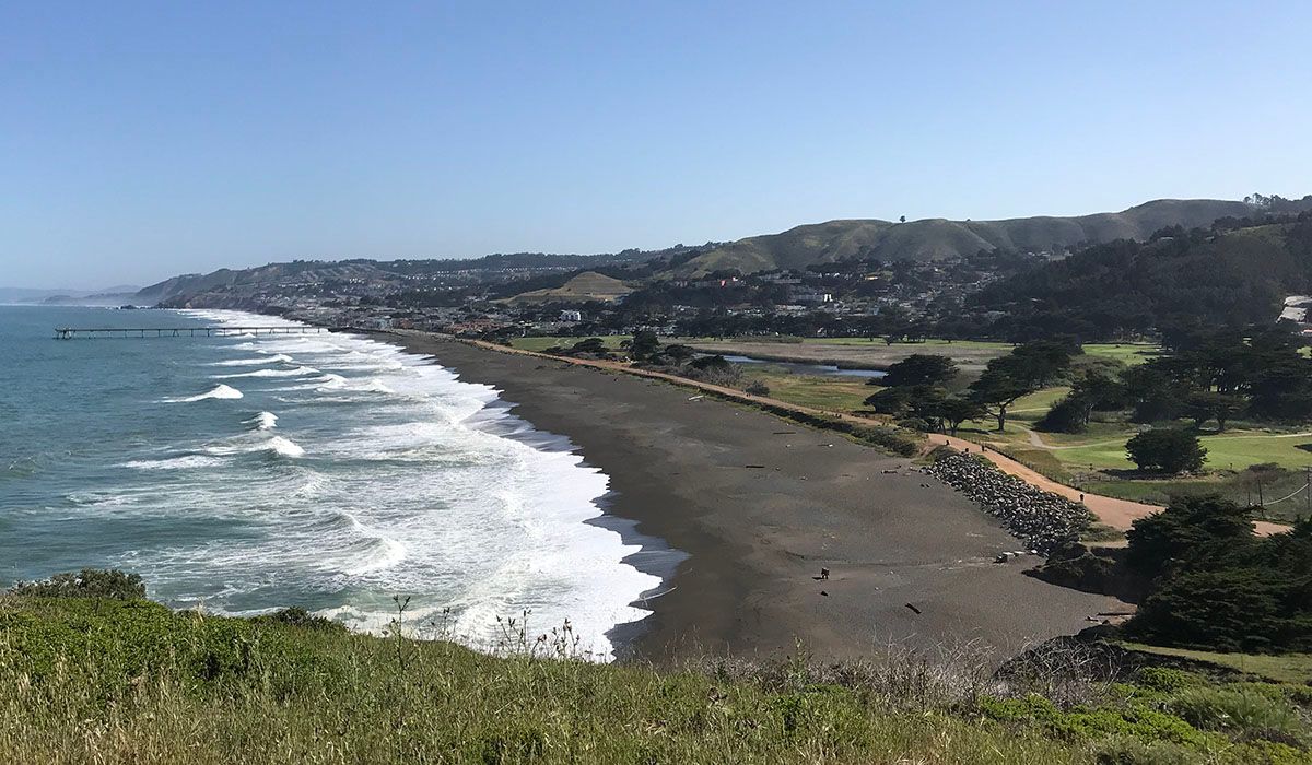 A view of a beach with waves crashing on the shore.