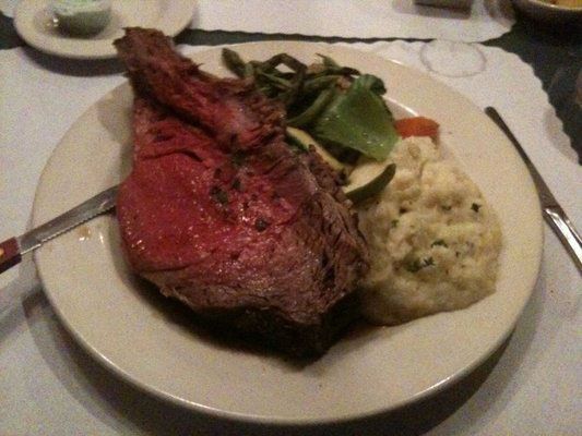 A white plate topped with a large piece of meat and mashed potatoes