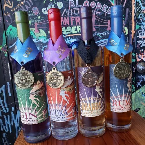Four bottles of alcohol with medals on them are sitting on a table.